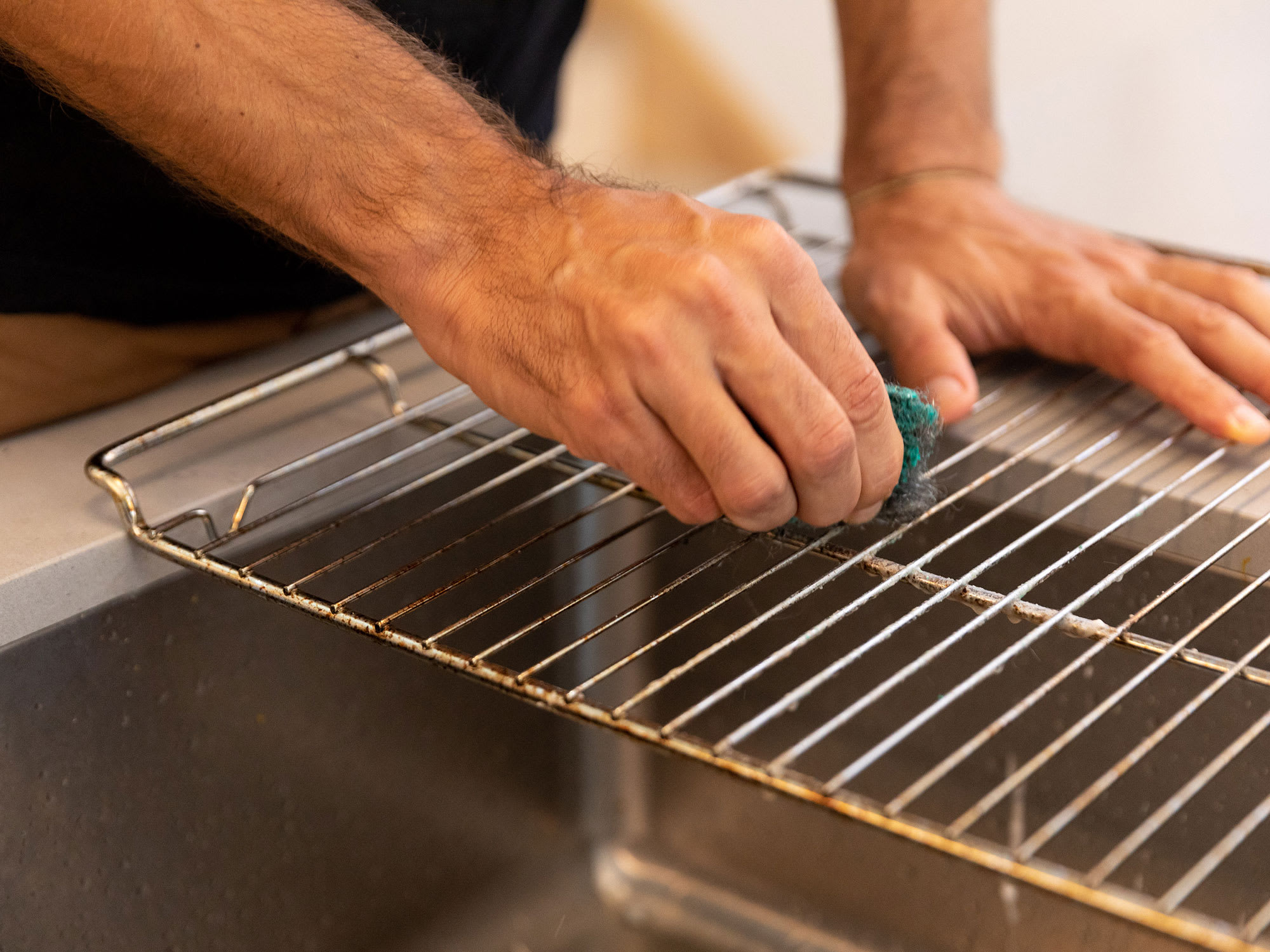 Scrubbing oven racks with scouring pad